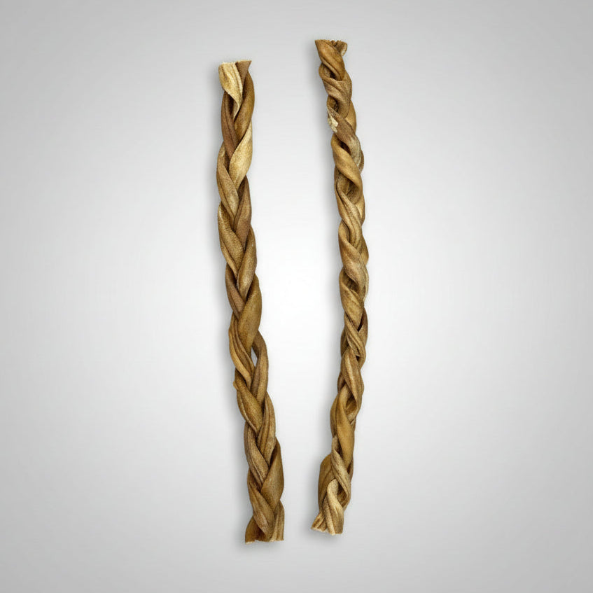 Two braided goat dog chews placed on a wooden surface.
